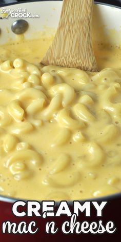 creamy mac n cheese is being stirred with a wooden spoon