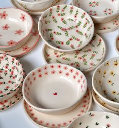 a collection of white and red dishes with flowers on them, all in different shapes and sizes