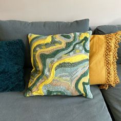 a couch with two pillows on it and one is yellow, the other has blue