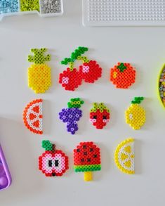 the beaded fruit and vegetable magnets are arranged next to a bowl of beads