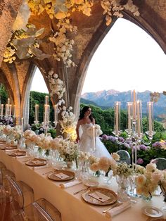 a woman in a wedding dress standing next to a table with flowers and candles