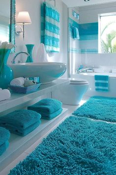 a bathroom with blue rugs and towels on the floor, in front of a bathtub