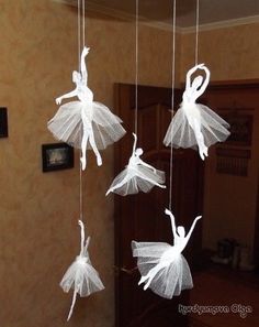 three white paper ballerinas hanging from strings