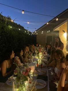 a group of people sitting at a table with food and drinks in front of them