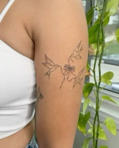 a close up of a person with a tattoo on her arm and behind her is a potted plant