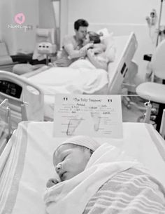 a black and white photo of a baby in a hospital bed next to an adult