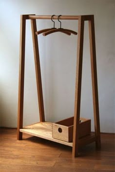 a wooden clothes rack with a drawer underneath it