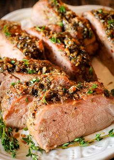 two pieces of meat on a plate with herbs