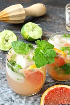 two glasses filled with watermelon and mint garnish on top of a wooden table