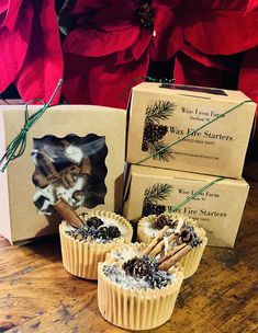 three cupcakes sitting on top of a wooden table next to two boxes with christmas decorations