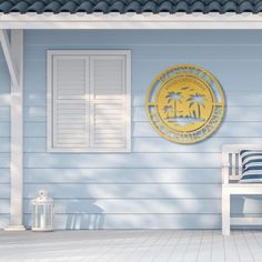 a white bench sitting next to a blue house with a yellow seal on the wall