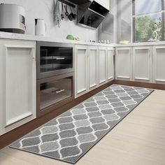 a kitchen with white cabinets and an area rug in front of the stove top oven