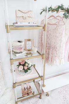 three tiered shelving unit with pink and white accessories