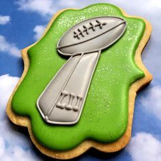 a cookie decorated to look like a football on top of a green field with white clouds in the background