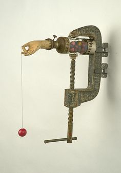 an old metal object hanging from the side of a wall next to a red apple