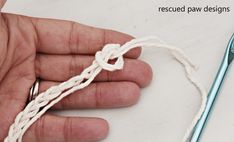 a person holding a piece of white yarn in their hand