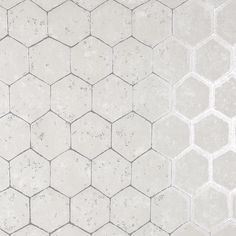 a white tiled wall with hexagonal tiles on the top and bottom, in grey tones