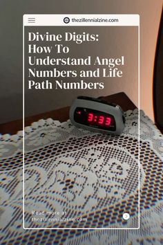 a digital alarm clock sitting on top of a table next to a wall with the words divine digits how to understand angel numbers and life path numbers