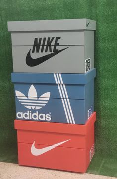 three adidas boxes stacked on top of each other in front of a green wall