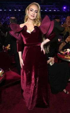 a woman in a red dress posing for the camera at an event with other people