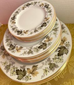 four plates stacked on top of each other with gold trimmings and leaf designs