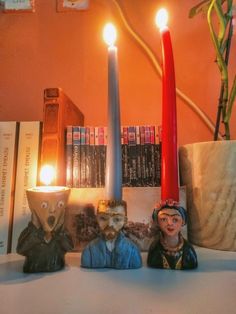 two figurines sitting next to a candle on top of a table with books