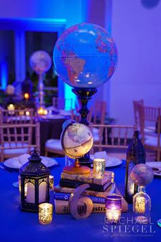 a table topped with lots of books and lit candles next to a globe on top of a book