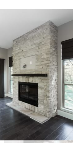 an empty living room with a stone fireplace