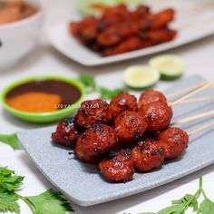 chicken skewers on a plate with dipping sauce and cilantro in the background