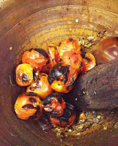 a wooden spoon in a bowl filled with tomatoes and other food items on top of it