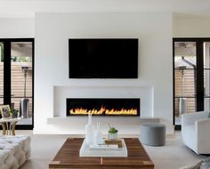 a living room with white furniture and a fire place in the middle of the room