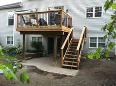 a wooden deck with stairs leading up to the upper floor and second story above it