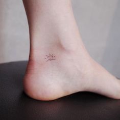 a small sun and moon tattoo on the right side of the foot, which is sitting on top of a table