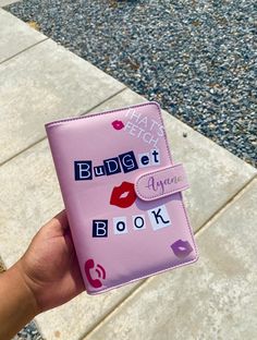 a person holding up a pink book with lipstick on it