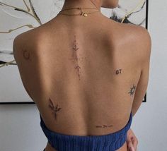 a woman with tattoos on her back standing in front of a painting