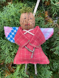 an angel ornament hanging from a christmas tree with pine cones on it's back