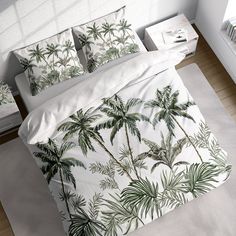 a bed with white sheets and green palm trees on the comforter, along with two nightstands