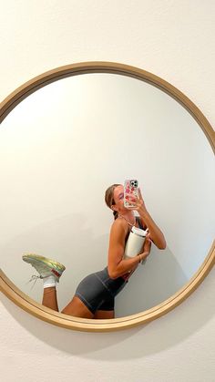 a woman taking a selfie in front of a mirror with her camera and water bottle