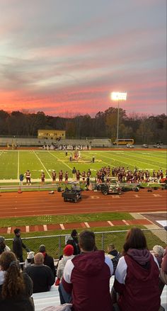 a football game is being played on a field with people sitting in the bleachers watching