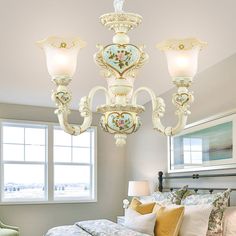 a chandelier hanging from the ceiling in a bedroom next to a bed with pillows on it