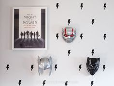 three masks are hanging on the wall next to a poster with lightning boltes and two black cats