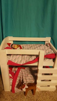 a wooden bunk bed with a red ribbon on the bottom and two deer figurines