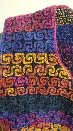 a multicolored crocheted blanket sitting on top of a table