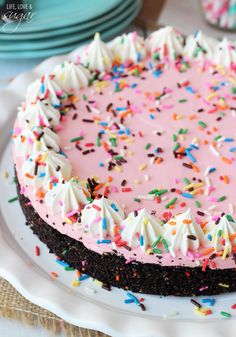 a cake with pink frosting and sprinkles on it sitting on a plate