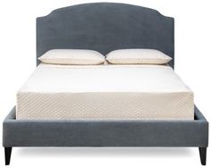 an upholstered bed frame with two pillows on the top and bottom, against a white background