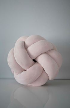 a pink knot sitting on top of a white table next to a gray wall and floor