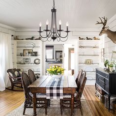 the dining room table is set with place settings for four people and has deer heads on the wall