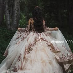 a woman in a dress is walking through the woods with her back to the camera