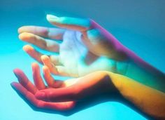 two hands with different colored powder on their palms and one hand holding something in the air