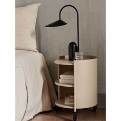 a table with a lamp on it next to a bed